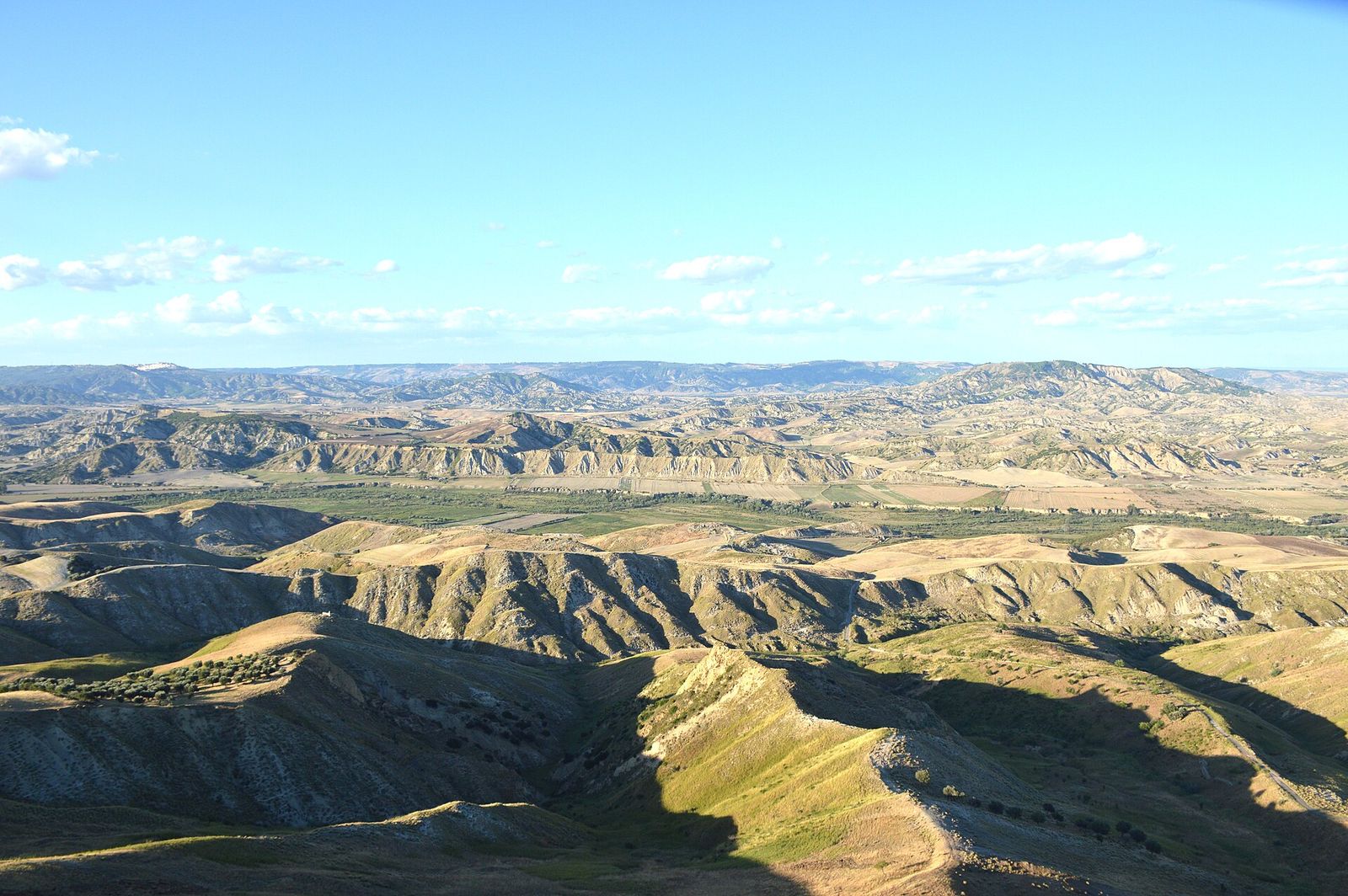 Colline argillose e calanchi della Basilicata sotto un cielo azzurro
